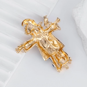 Golden scarecrow clown pin with vintage enamel finish on white stone background