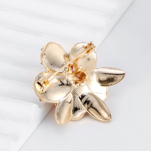 Broche pivoine dorée élégante avec fermoir de sécurité sur support texturé blanc