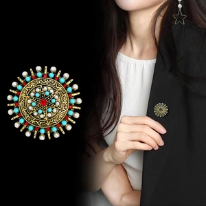 Bohemian vintage round brooch with pearl and ruby beads shown on black blazer
