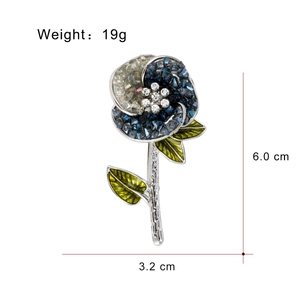 Broche fleur élégante avec cristaux bleus et feuilles vertes sur base argentée