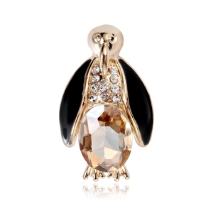 Detail of penguin brooch featuring gold metal, black enamel, and champagne crystal