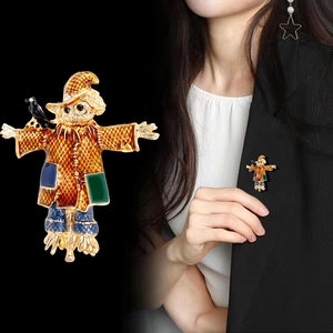 Cartoon scarecrow enamel brooch with black crow detail on a dark suit lapel