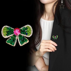 Détail de la broche nœud en cristal avec pierres vertes et grand cabochon rose rouge