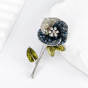 Broche rose élégante avec cristaux bleus et feuilles émaillées sur fond de pierre