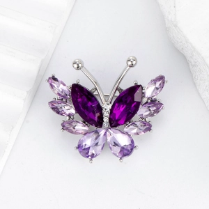 Elegant purple crystal butterfly brooch with silver base on white stone background