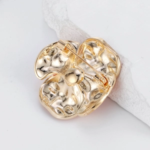 Minimalist gold camellia flower brooch with detailed back pin closure and textured alloy finish