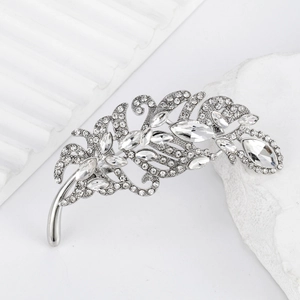 Elegant silver feather brooch with sparkling crystals on a textured stone display