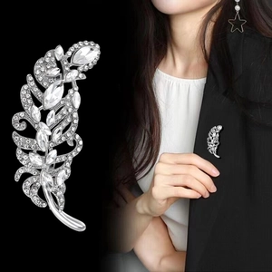 Vintage silver feather brooch with marquise crystals shown on a black suit lapel