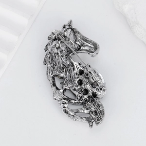Vintage silver horse head brooch back view showing metal safety pin on textured stone