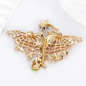 Golden bat wing brooch with green gemstone inlay showing the secure safety pin back