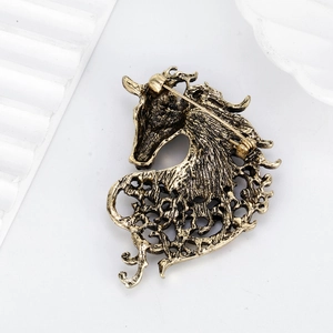 Vintage gold horse head brooch with intricate hollow design and secure safety pin back