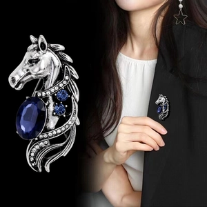 Vintage silver horse head brooch featuring a large oval blue gemstone on a black suit