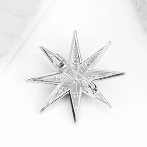 Silver octagonal star brooch with sparkling crystals and secure pin on white stone