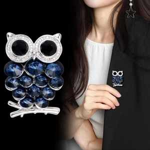 Luxurious owl brooch with blue crystals and sparkling diamonds on a silver branch
