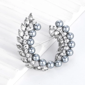 Elegante broche de corona plateado con perlas grises y cristales sobre blanco