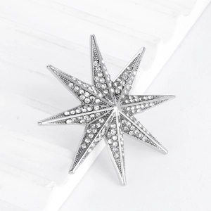 Silver octagonal star brooch with sparkling rhinestones on a white geometric display
