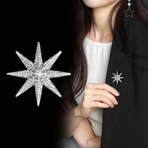 Sparkling silver octagonal star brooch with crystals shown on a black suit blazer