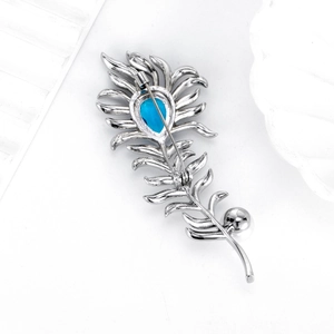 Exquisite peacock feather brooch with blue gemstone in a silver metal finish