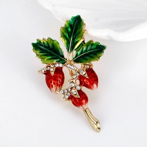 Elegant strawberry brooch with green leaves and red enamel details on white background
