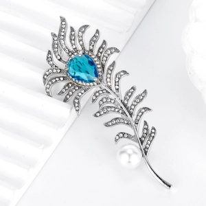 Elegant silver feather brooch featuring blue drop gemstone, crystals and a white pearl