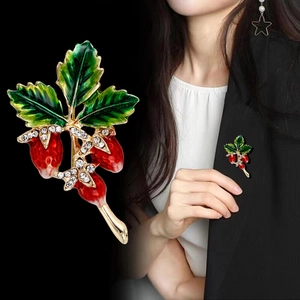 Green enamel leaf and berry brooch with sparkling crystals on a black suit lapel
