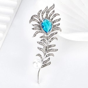 Exquisite crystal feather brooch with blue gemstone and pearl on white background