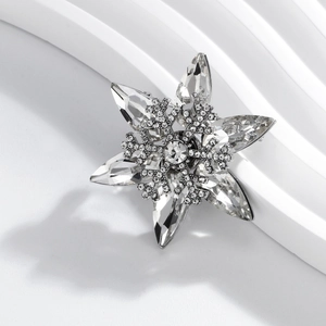 Elegant snowflake brooch with crystal rhinestones on a minimalist white architectural stand