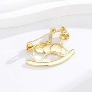 Minimalist golden rocking horse brooch showing the back metal pin and polished texture