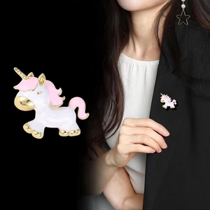 Détail de la broche licorne blanc et rose avec accents dorés sur un revers noir