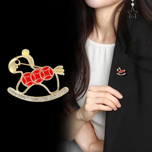 Golden rocking horse brooch with red enamel and crystals on a black suit lapel