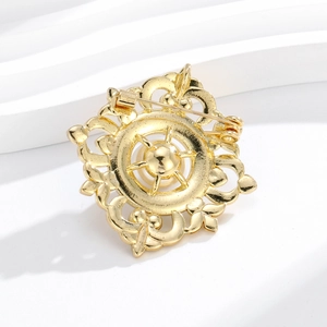 Vue arrière de broche vintage dorée montrant la gravure évidée et le fermoir épingle