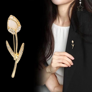 Détail de la broche tulipe en cristal avec opale et strass sur le revers d'un tailleur