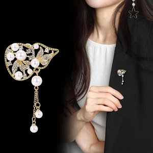 Détail de broche vintage française avec perles et pompons dorés sur une veste de blazer