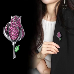 Gros plan et guide de style d'une broche rose vintage avec cristaux rouges et émeraude verte