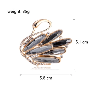 Elegant gold swan brooch with grey crystals and white rhinestones on white background