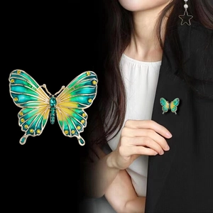 Detail of green and yellow enamel butterfly brooch with gold plating on dark blazer