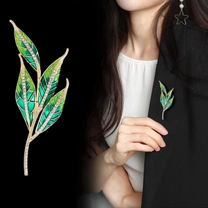 Elegant green leaf enamel brooch with sparkling crystals on black blazer lapel