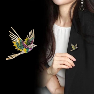 Elegant bird brooch with colorful enamel wings and rhinestones on black suit jacket