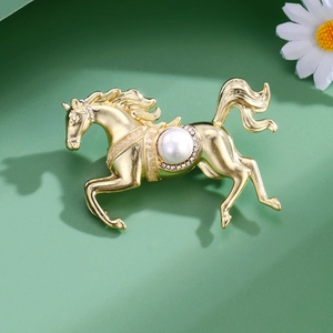 Broche cheval dorée élégante avec perle et cristaux brillants sur fond vert nature