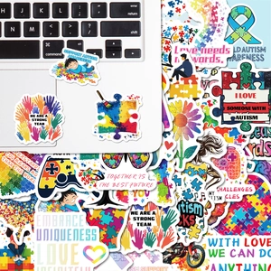 Detail showing various autism awareness stickers with puzzle hearts on a laptop
