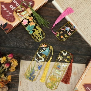 Set of four hollow metal bookmarks with oriental motifs and silk tassels on wood