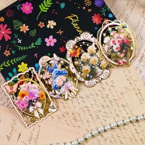 Dettaglio di quattro segnalibri in metallo vintage con motivi floreali e nastri