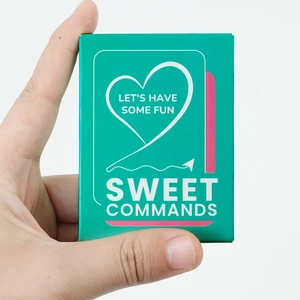Close-up of mint green Sweet Commands game box with heart design and Let's Have Some Fun text