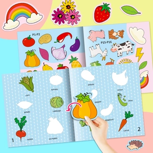 Macro view of kids vegetable sticker book showing a hand placing a pumpkin decal on the page