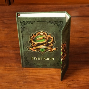 Détail du carnet de magie vert avec emblème de serpent doré sur bureau en bois