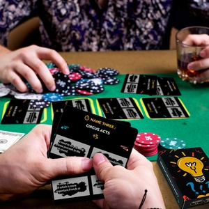 Macro shot of Name Three game cards and poker chips on green felt with adult party vibes