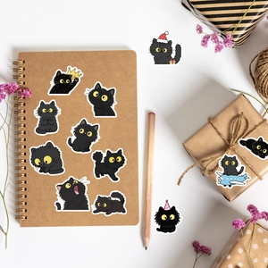 Détail d'autocollants chat noir mignon sur un carnet kraft avec décorations florales