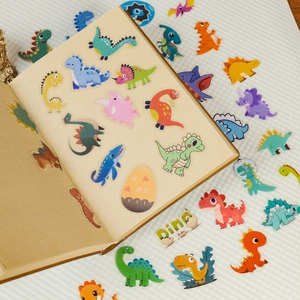 Close-up of cute cartoon dinosaur PET stickers on a notebook with colorful dino patterns