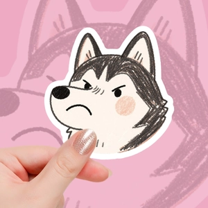 Nahaufnahme einer Hand, die einen niedlichen Husky-Aufkleber mit wasserfestem Finish hält