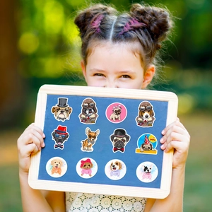Close-up of a girl holding a display board with 12 colorful cartoon dog stickers outdoors